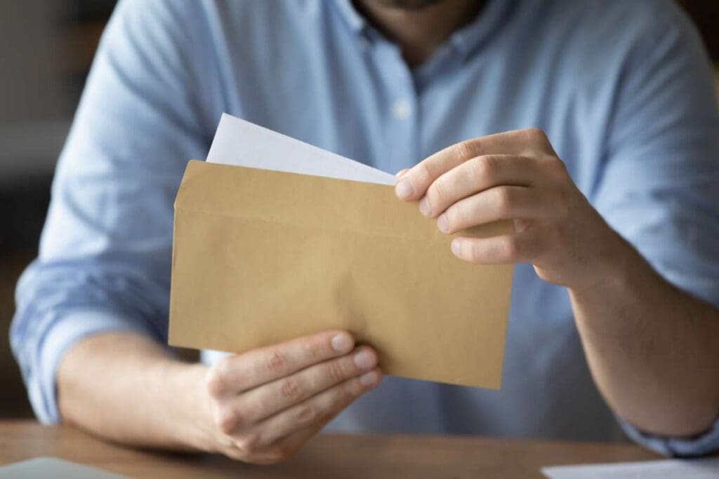 A businessman removes a letter from an envelope. 